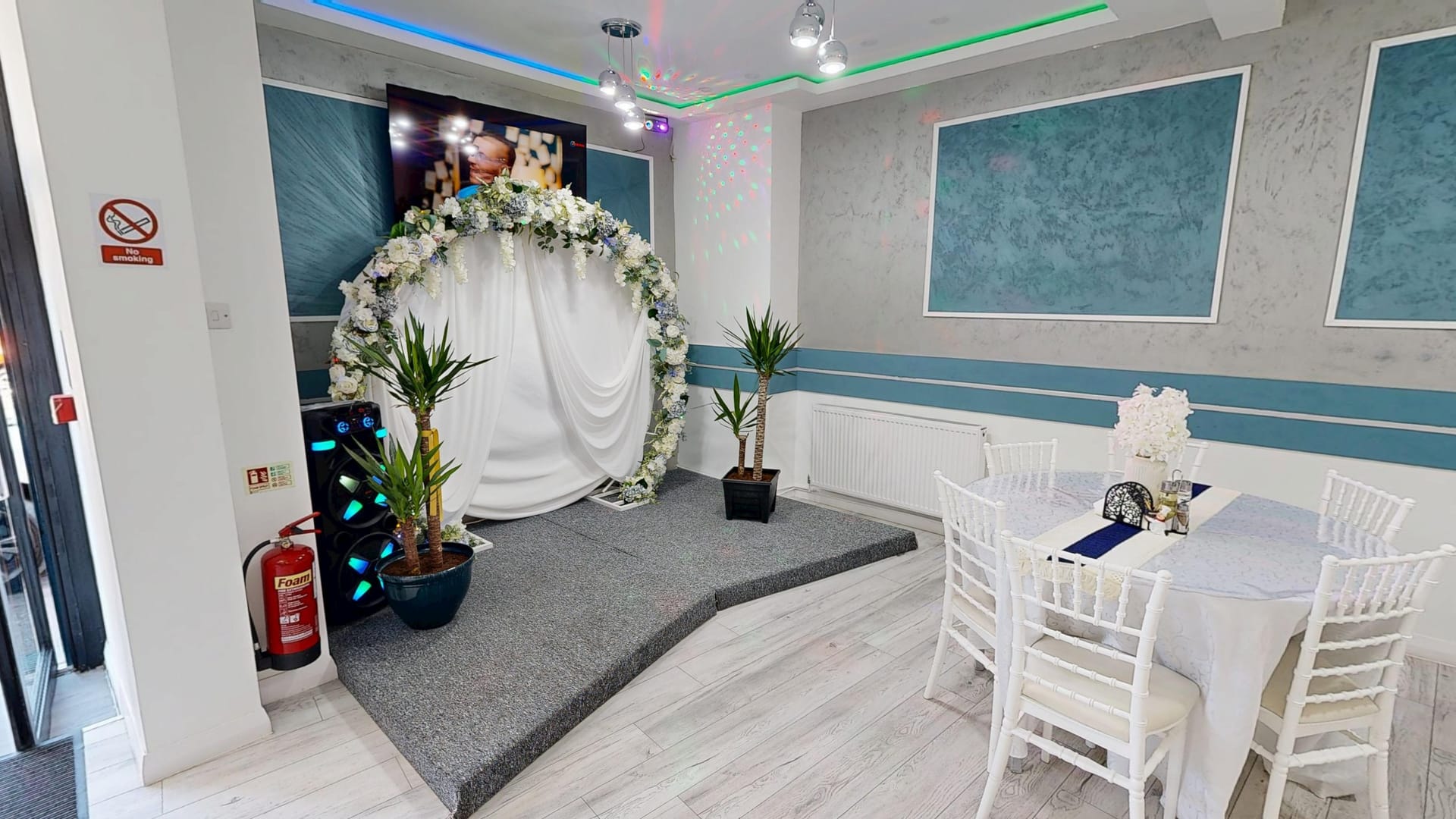 Event space at Restaurant Acasă with a floral arch backdrop and a small stage