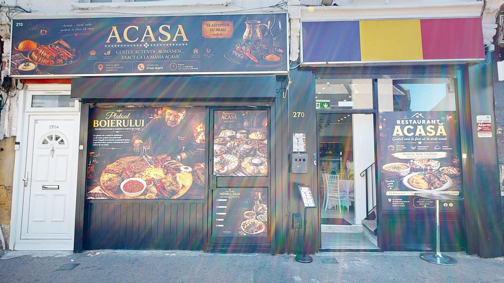 The Restaurant Acasă shopfront on High Road, Leytonstone, with the Romanian flag and the entrance open