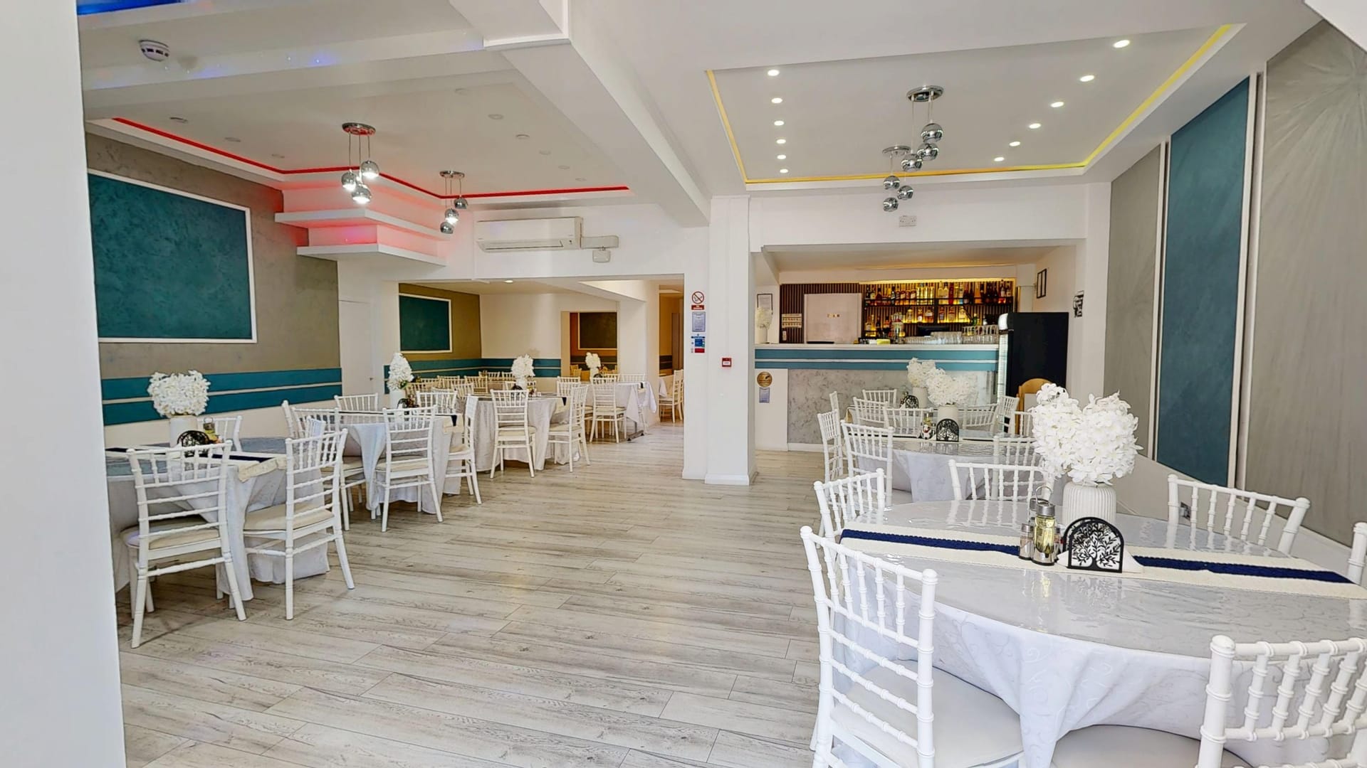 The main dining hall at Restaurant Acasă, set with round tables and white Chiavari chairs